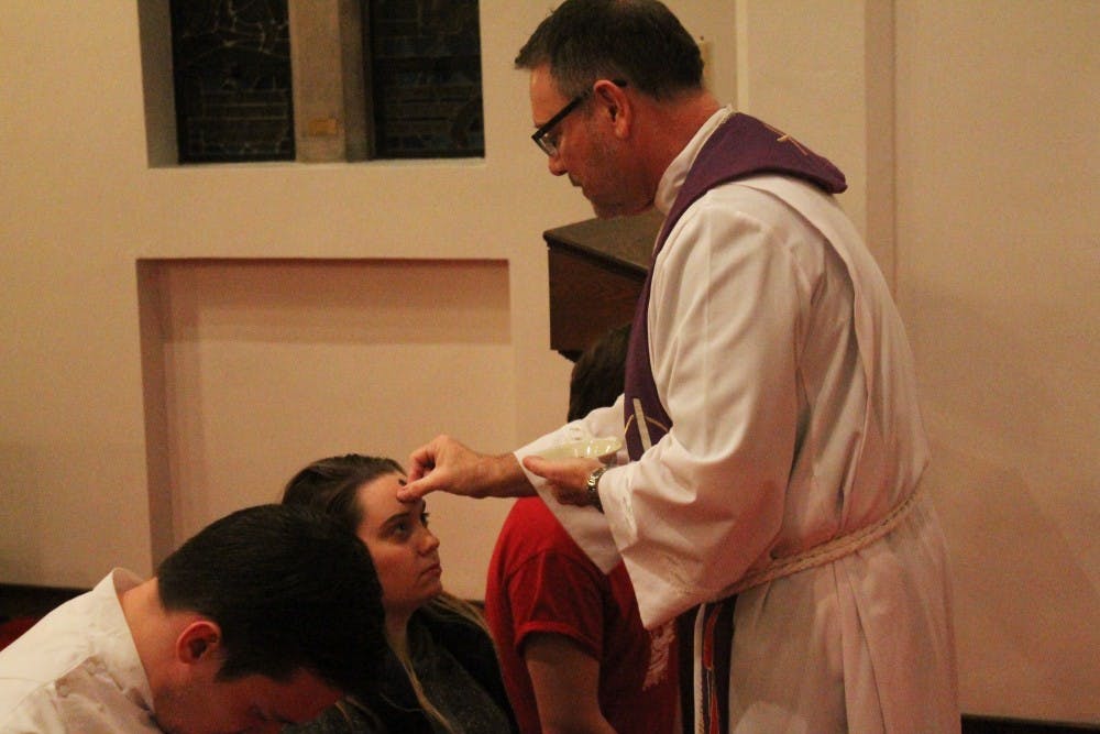 Pastor Richard Woelmer of University Lutheran Church bestows ashes onto the foreheads of churchgoers. This event took place at 7 p.m. Wednesday.