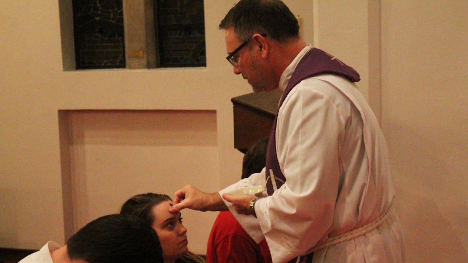 Pastor Richard Woelmer of University Lutheran Church bestows ashes onto the foreheads of churchgoers. This event took place at 7 p.m. Wednesday.