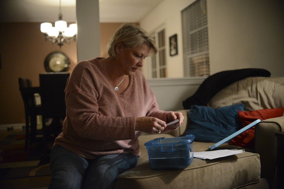 Robin Wilson goes through old photos of Hannah at her home in Noblesville, Ind. The blue box holds Hannah’s “entire life.” The box contained photos displayed at her funeral. Days before Hannah’s funeral several people gathered in her living room to help the family prepare and put the hundreds of photos on the display boards.
