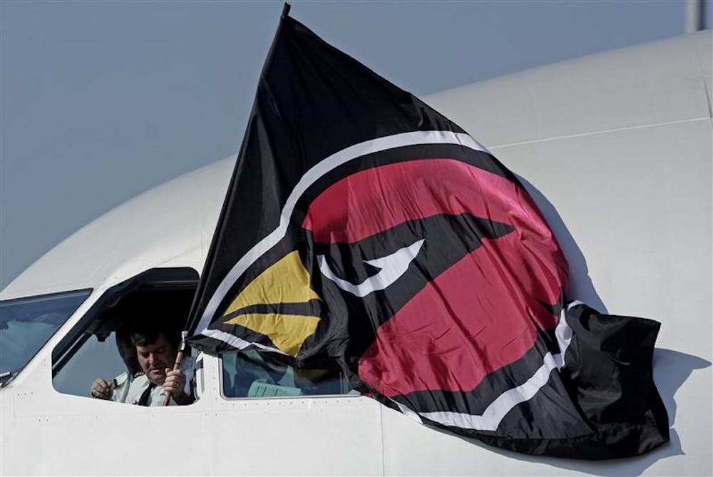Capt. Bruce Meyer of Minneapolis holds a Arizona Cardinals flag outside the cockpit window as the team arrives at the Tampa International Airport for Super Bowl XLIII NFL football game  Monday in Tampa, Fla. 