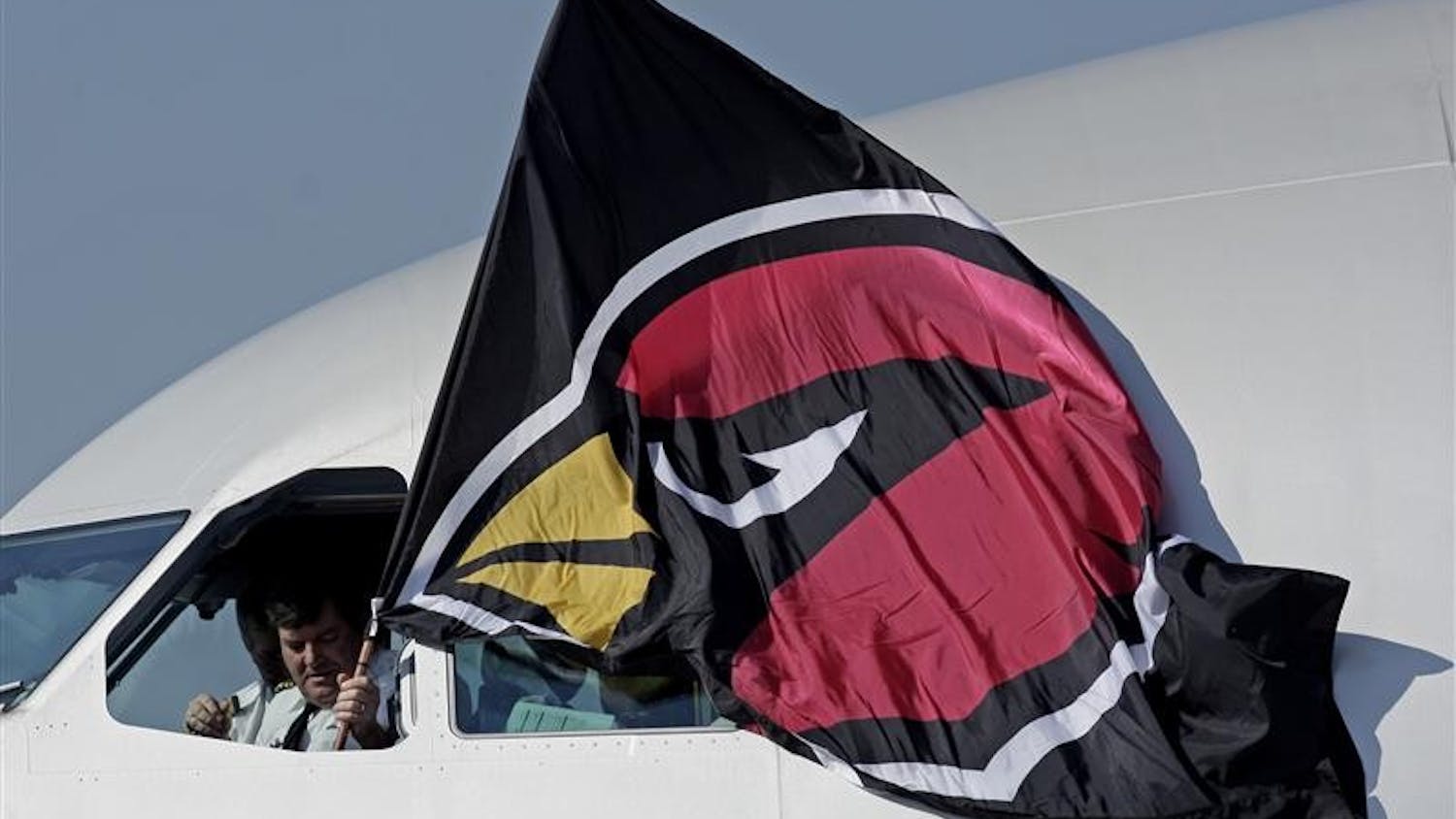 Capt. Bruce Meyer of Minneapolis holds a Arizona Cardinals flag outside the cockpit window as the team arrives at the Tampa International Airport for Super Bowl XLIII NFL football game Monday in Tampa, Fla.