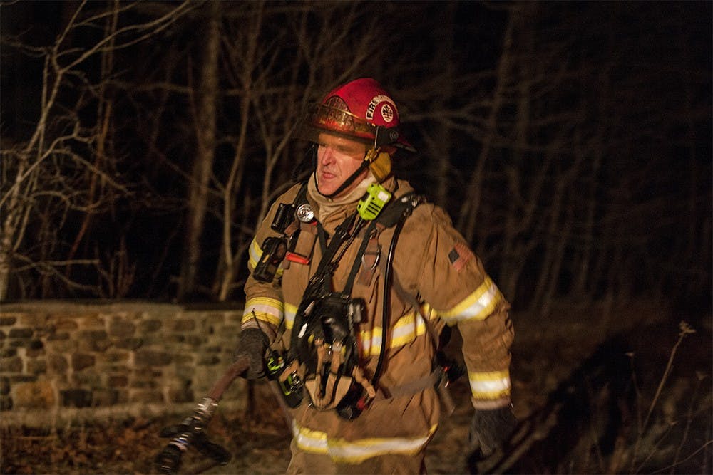 Firefighter Bart Epler pulls a hose around a burning house to continue fighting the fire from the opposite side of the house.