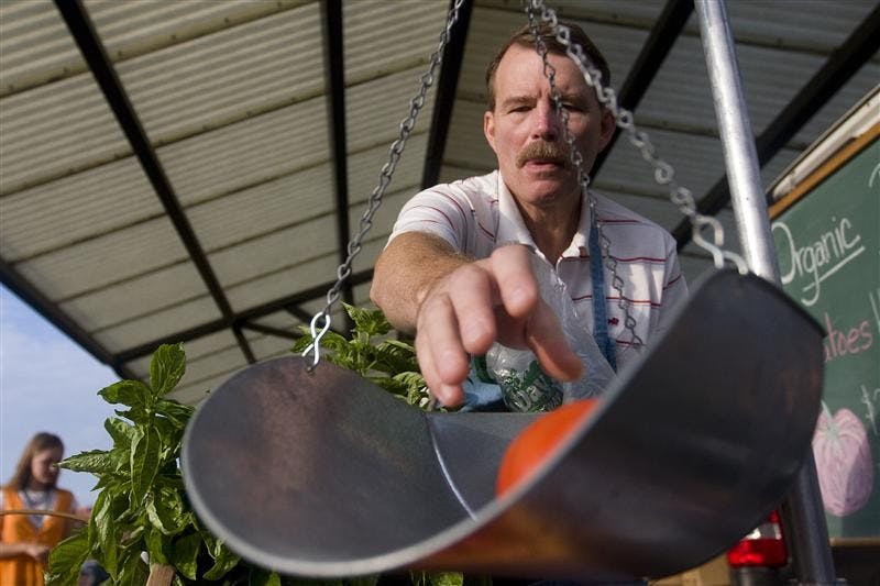 Art Jacques weighs tomatoes for a customer on Saturday, Sept. 13, at the Farmers' Market.