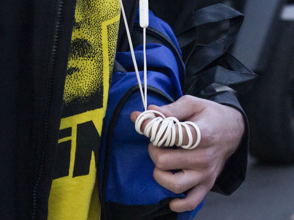 Abe wraps the cord of his headphones around his fingers as he talks to a friend on the street. He uses the headphones to block out sounds. “My ears would probably explode if I went to a rave,” he said.