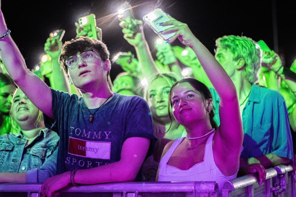 周六晚上，在印第安纳州纪念联盟的街区派对上，音乐会的观众们随着音乐挥舞着手机。
