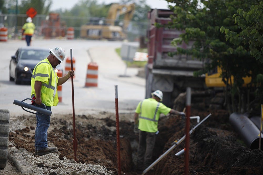 Jeff Gott, a superintendent with Milestone Contractors, drives beams into the ground on Jordan Ave. Wednesday.  Construction has been slowed down by the rain, but construction workers have been working through the rain to get the job done, he said.
