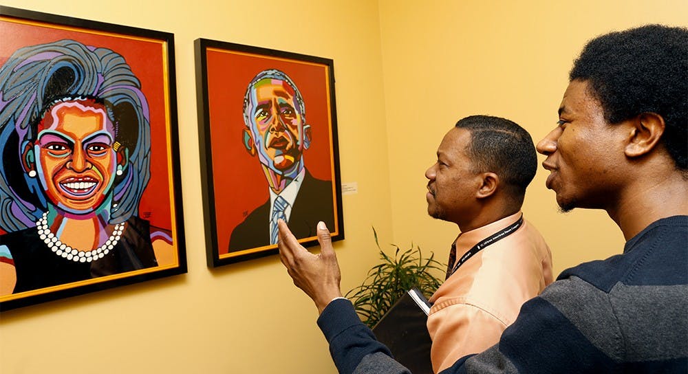 Raymond Wise, left, and Shaquile Hester look at the portraits of President Barack Obama and First Lady Michelle Obama Monday at Neal-Marshall Black Culture Center. The portraits were drawn by Joel Washington, a local artist and a staff at the Indiana Memorial Union, and hung on the Wall of Firsts among other portraits to celebrate President Day and Black History Month. 