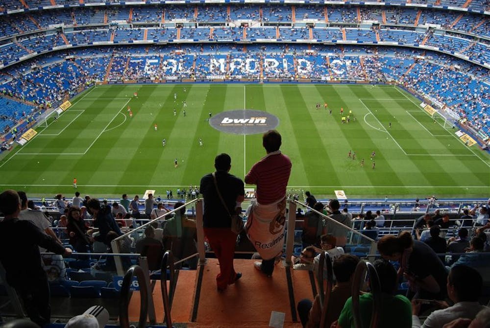 Two spectators watch warm-ups before a soccer game between Real Madrid and Club Atlético Osasuna May 2 at Santiago Bernabéu Stadium in Madrid. Real Madrid is currently in second place behind FC Barcelona in the Primera División regular-season standings.