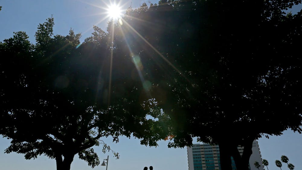 Beachgoers enjoy the shade and sea breeze beneath trees at Valparaiso Plaza on Friday in Long Beach, California. A weather event this week has the potential to set all-time record high temperatures throughout Southern California.