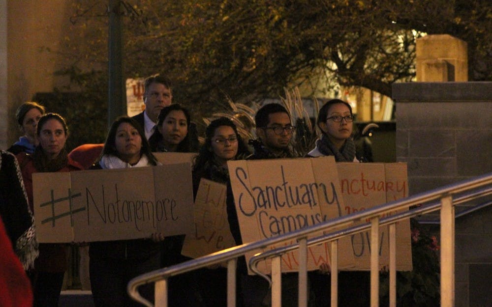 Students stand in the front row of the crowd holding signs. The crowd gathered in the Fine Arts Plaza on Thursday evening for a unity talk sponsored by IU administration and student organizations.