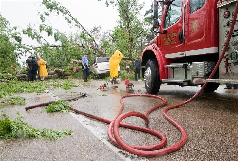 Emergency crews from the Missouri State Highway Patrol, Butler County and Poplar Bluff clean up the scene of an accident on Missouri Highway 53, about three miles south of Poplar Bluff, Mo., Friday. The vehicle was traveling south when gusty storm winds apparently uprooted a large oak tree, which fell on the vehicle, killing both occupants.