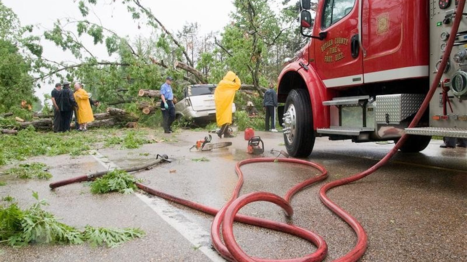 Emergency crews from the Missouri State Highway Patrol, Butler County and Poplar Bluff clean up the scene of an accident on Missouri Highway 53, about three miles south of Poplar Bluff, Mo., Friday. The vehicle was traveling south when gusty storm winds apparently uprooted a large oak tree, which fell on the vehicle, killing both occupants.