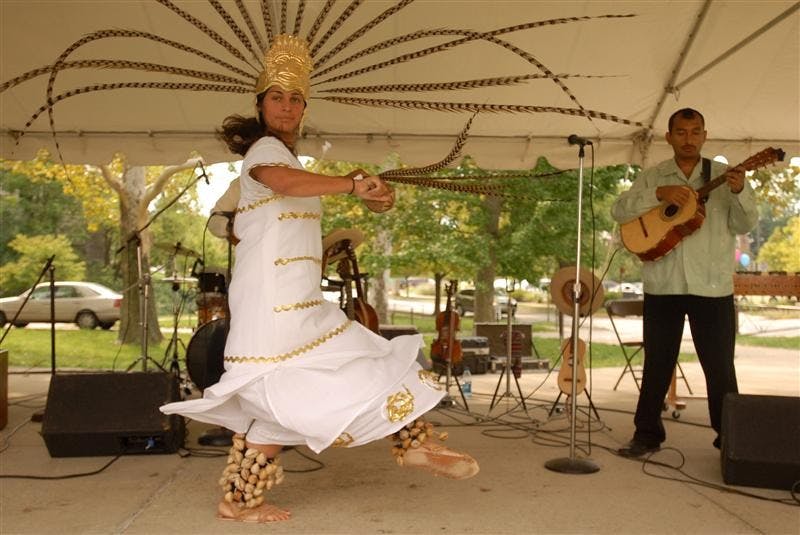 Members of Chicago based Grammy-nominated Mexican folk band Sones de Mexico dancer Lorena Iñiguez (left) and string instrumentalist Victor Pichardo (right) perform an Aztec ceremonial dance and song during Festival Latino Saturday afternoon in Dunn Meadow. Besides several music and dance performances, the event featured booths of local organizations and fraternities, food stations and sumo wrestling suit matches.