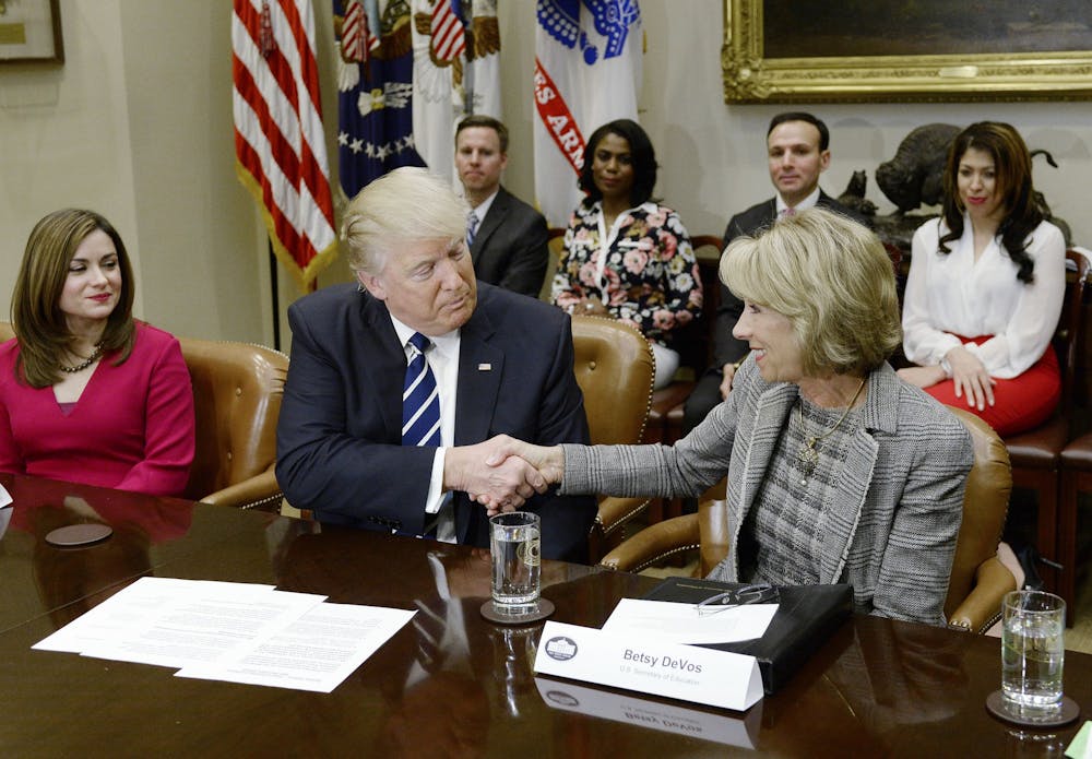 President Donald Trump shakes Education Secretary Betsy DeVos' hand during a parent-teacher conference listening session Feb. 14, 2017, in the Roosevelt Room of the White House in Washington, D.C.