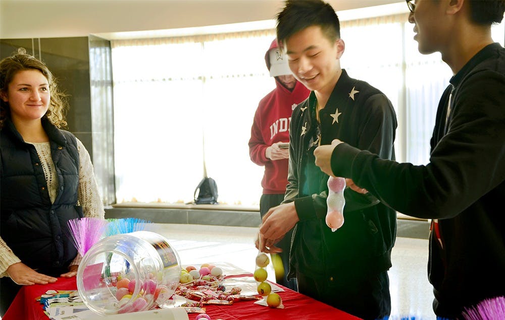 Yaolun Wu, center, and Zhipeng Gu challenge the one minute condom game during the "Sex Fest" event hosted by Willkie and Teter Residence Centers Saturday. They filled four balls into the condom in one minute carefully. Gu said that they came to this event for their human sexuality class. 