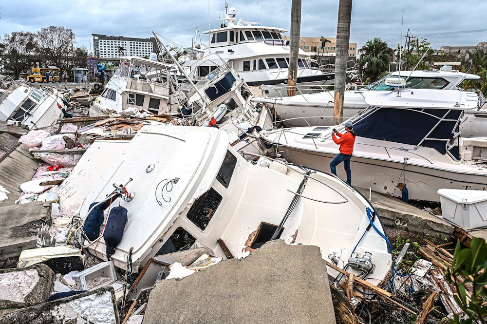 <p>A man takes photos of boats damaged by Hurricane Ian on Sept. 29, 2022, in Fort Myers, Florida. Hurricane Ian hit the Florida southwest coast Wednesday morning with wind speeds upwards of 150 mph, leaving many residents helpless amid a constant downpour.  </p>