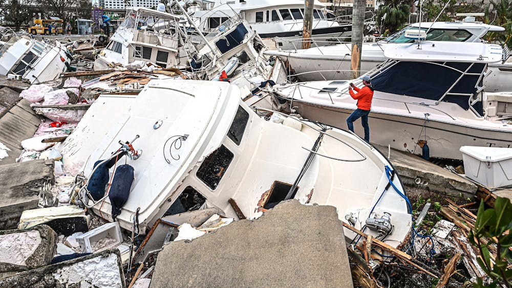 A man takes photos of boats damaged by Hurricane Ian on Sept. 29, 2022, in Fort Myers, Florida. Hurricane Ian hit the Florida southwest coast Wednesday morning with wind speeds upwards of 150 mph, leaving many residents helpless amid a constant downpour.  