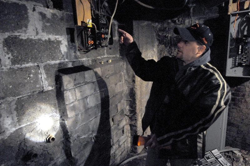 Carl Thoms, of Terre Haute, points to a basement wall that hides a hidden room in his home on Sunday on Mulberry Street in Terre Haute.