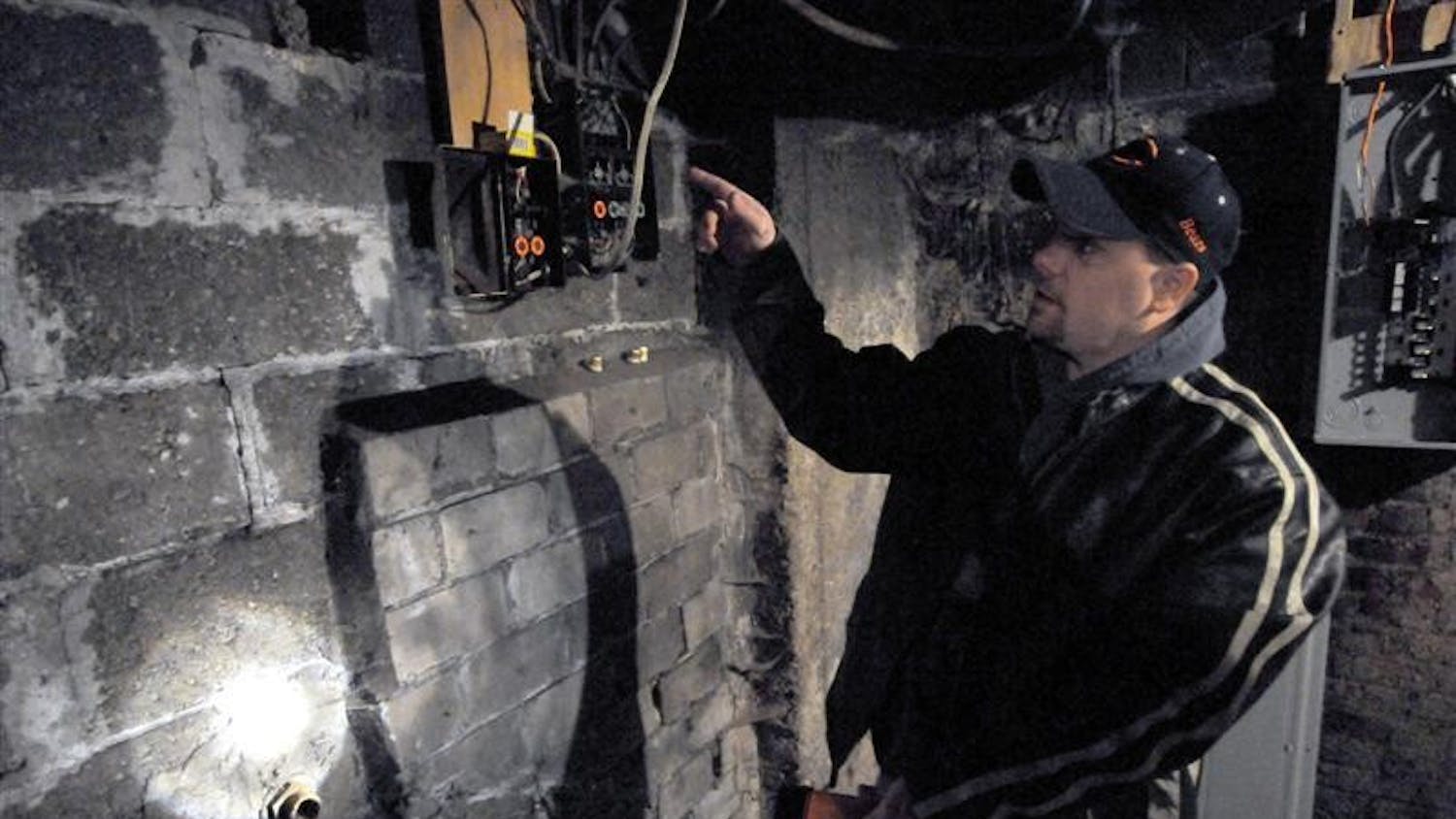 Carl Thoms, of Terre Haute, points to a basement wall that hides a hidden room in his home on Sunday on Mulberry Street in Terre Haute.