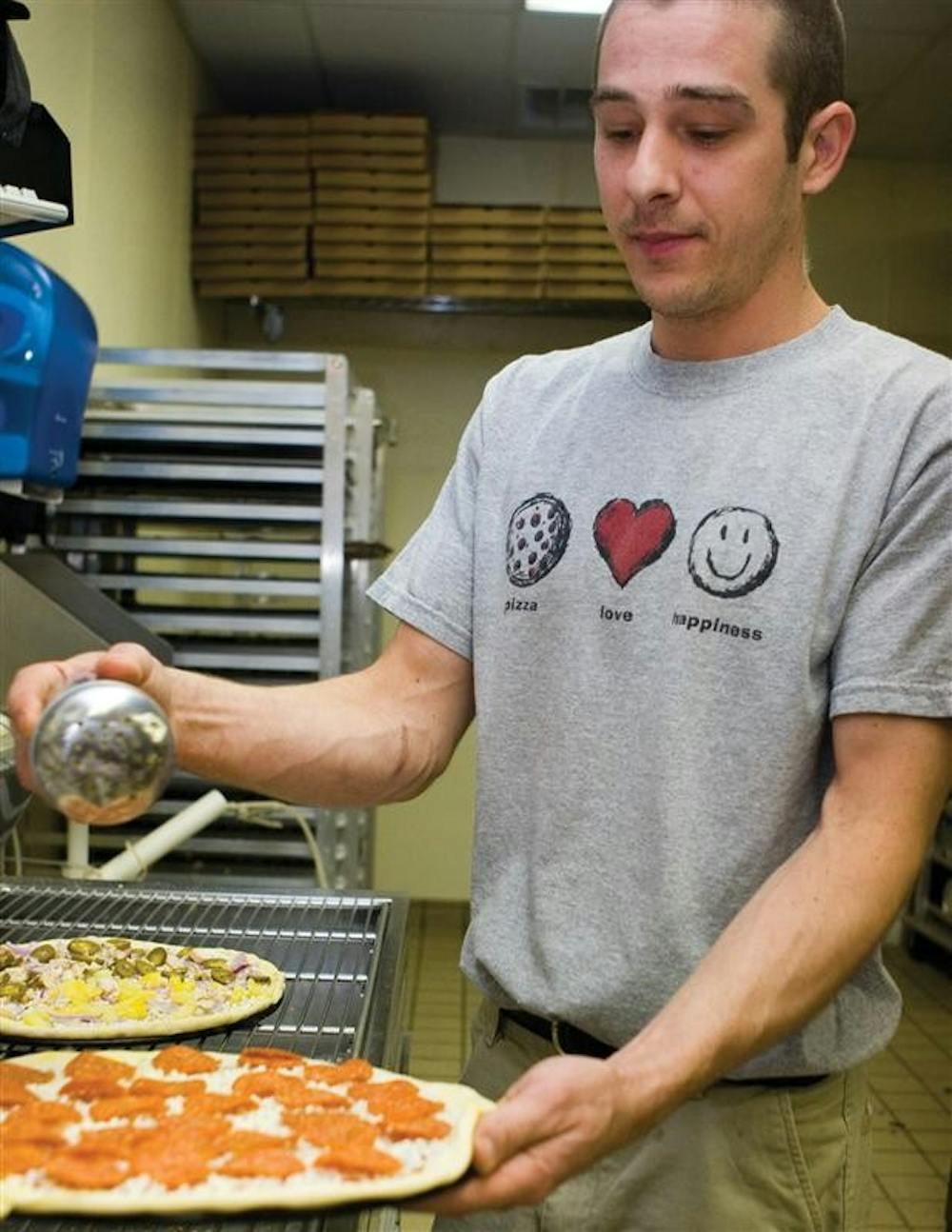 Pizza Express employee John Reidy puts the final touches on a pizza before putting it in the oven Thursday, May 3, 2007 at the Pizza Express on East Tenth Street.  