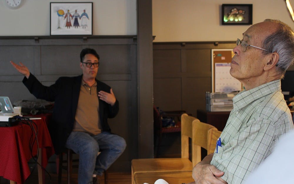 Chinese calligrapher James Yang listens intently to Jason Jackson discuss his trips to China at the First Nations Educational and Cultural Center. Yang is an artist working with the Mathers Museum of World Cultures who would love to visit China as well.