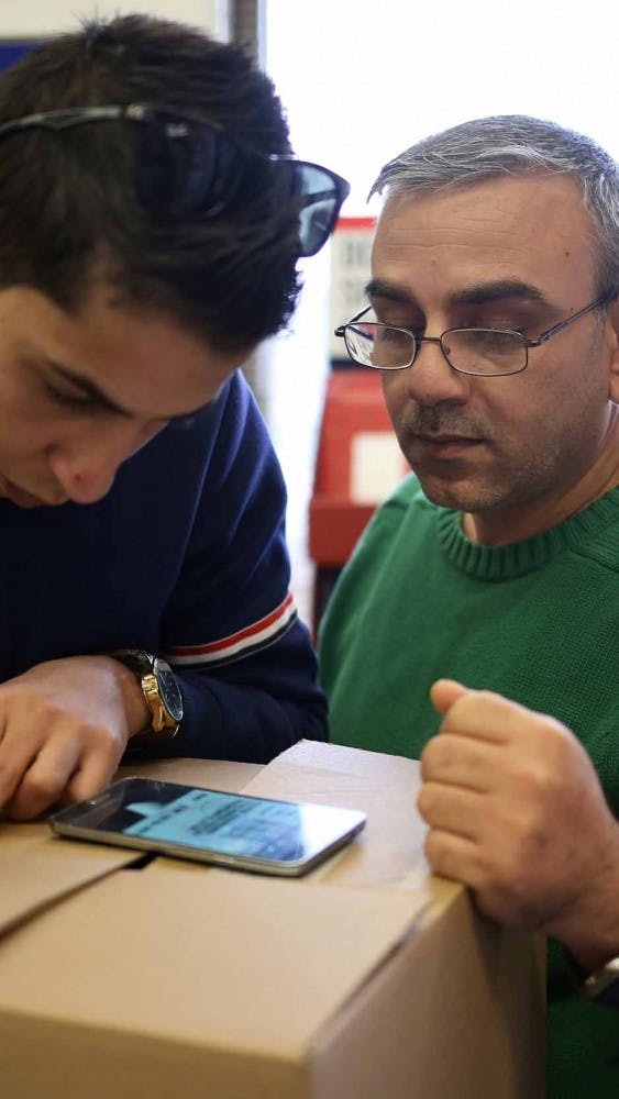 Marwan and his co-worker, Mohammed, struggle together at the Post Office to send a package to Illinois on Dec. 3. They accidentally wrote the "to" address in the "from" box so the postal worker had to give them a label to re-do it.