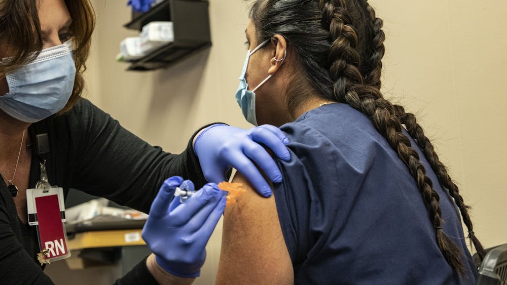 Community Health Services Clinical Manager Amy Meek injects the first round of the COVID-19 vaccine into Medical Assistance frontline worker Zaira Hernandez’s left arm Dec. 18, 2020 at the Employee Health Services building in Bloomington. “This is just an extra barrier,” Hernandez said when discussing what it means to receive the first vaccine in Bloomington.
