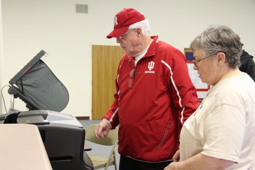 Helen Kane helps a voter scan his ballot in the machine during her first-ever shift as a poll worker.
