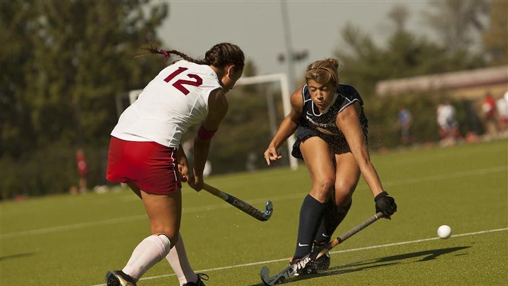 Danielle McNally hits the ball by a shuddering Nittany Lions offensive player Friday at the IU Field Hockey Complex.
