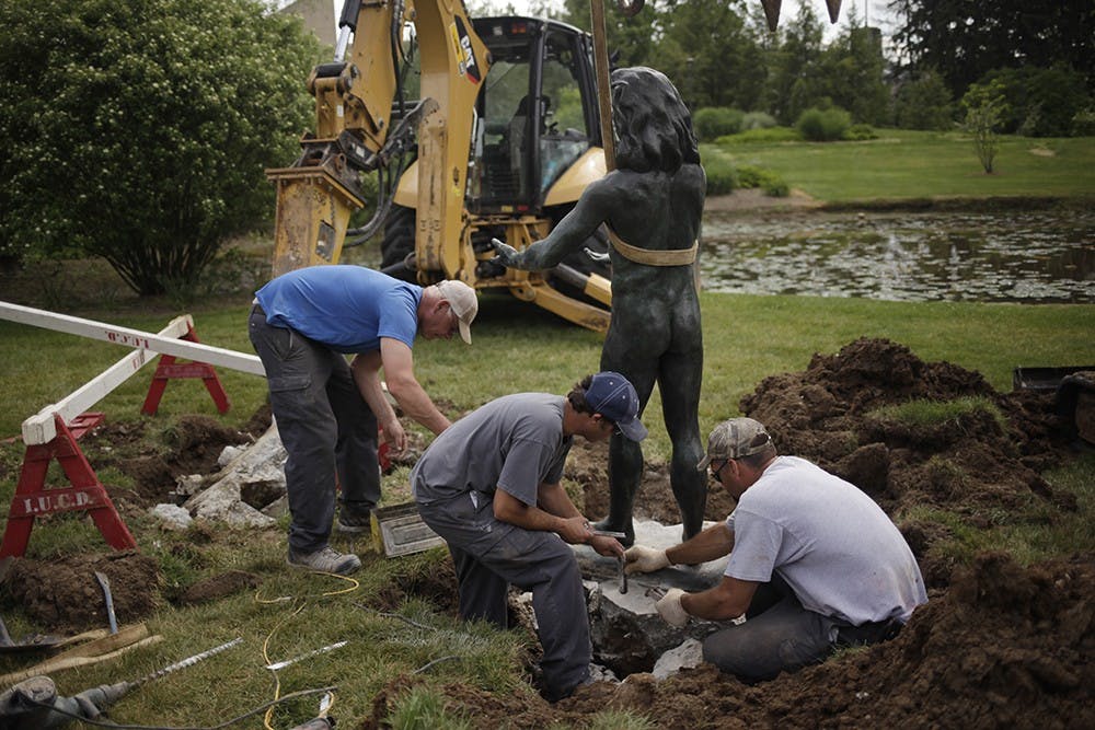 IU construction workers, from left, Carlos Webb, Vance Feutz, and David Jones remove concrete from the remaining Anthony Droege sculpture in the IU Arboretum on Tuesday.  The two sculptures originally put in place featured Adam and Eve.  The Eve sculpture was reported missing Tuesday morning.  "Whoever took the sculpture shook it back and forth until it ripped off the foundation," says Webb.  "It's a real shame, it looked really nice down here."   