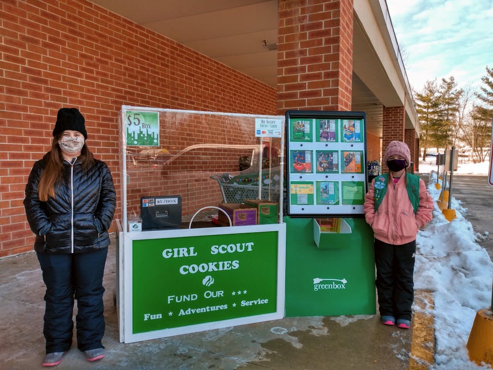 <p>安斯利和雷恩·弗格森合影留念一名女童子军为3154部队出售饼干的地点。布卢明顿的Grubhub提供八种女童子军饼干</p>