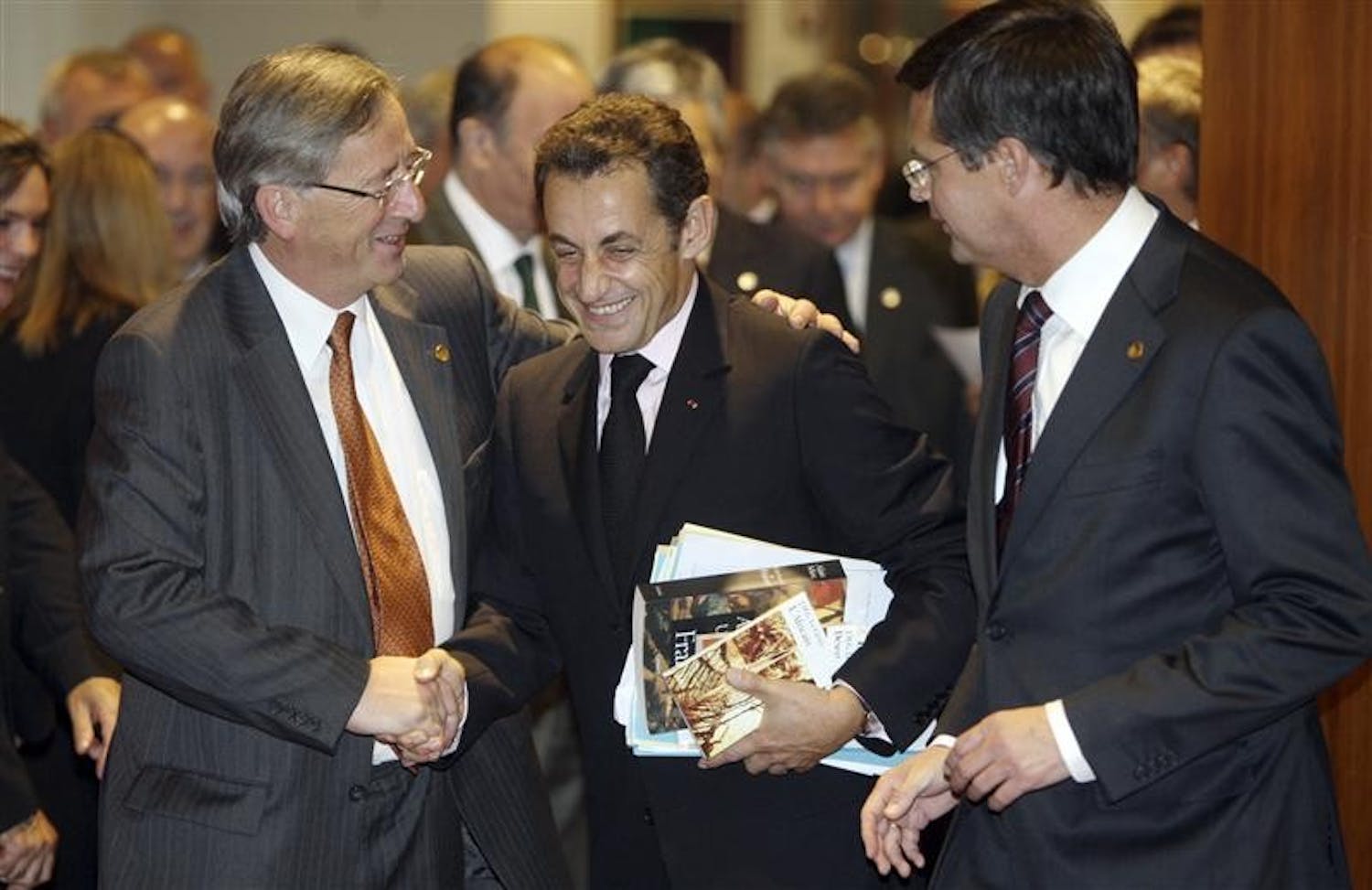 French President Nicolas Sarkozy, center, shares a word with Luxembourg's Prime Minister Jean Claude Juncker, left, and Dutch Prime Minister Jan Peter Balkenende as they enter a round table meeting Wednesday during an EU summit in Brussels. Efforts to calm the impact of the global financial crisis will top the agenda at a two-day EU leaders summit along with talks on how the 27-nation bloc can keep on track ambitious promises to cut greenhouse gas emissions by 20 percent by 2020.