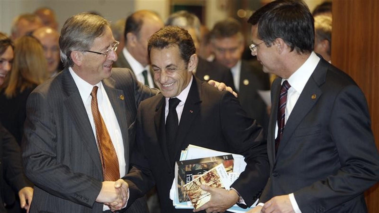 French President Nicolas Sarkozy, center, shares a word with Luxembourg's Prime Minister Jean Claude Juncker, left, and Dutch Prime Minister Jan Peter Balkenende as they enter a round table meeting Wednesday during an EU summit in Brussels. Efforts to calm the impact of the global financial crisis will top the agenda at a two-day EU leaders summit along with talks on how the 27-nation bloc can keep on track ambitious promises to cut greenhouse gas emissions by 20 percent by 2020.