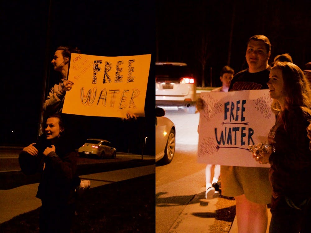Freshmen Chi Alpha members Hanna and Jennifer Dearman, left, hold up a sign advertising free water Friday at the intersection of 17th Street and North Jordan Avenue. Freshman Alex Huey and senior Heidi Holtsclaw, right, hold up a sign advertising free water to cars as they drive by. Members of Chi Alpha handed out free water bottles Thursday, Friday and Saturday nights to partygoers at known drinking locations throughout Bloomington in honor of Little 500 weekend.
