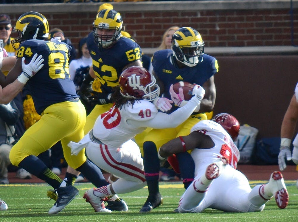 Sophomore safety Antonio Allen and senior defensive tackle Bobby Richardson make a tackle during IU's game against Michigan on Saturday at Michigan Stadium.