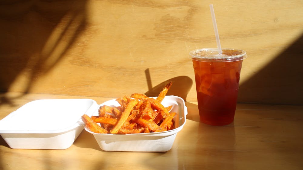 A side order of sweet potato fries with an iced tea from the Owlery sits in the sun Monday. Sweet potato fries are one of the items you can get as part of the Owlery’s Devour Bloomington take-out menu.