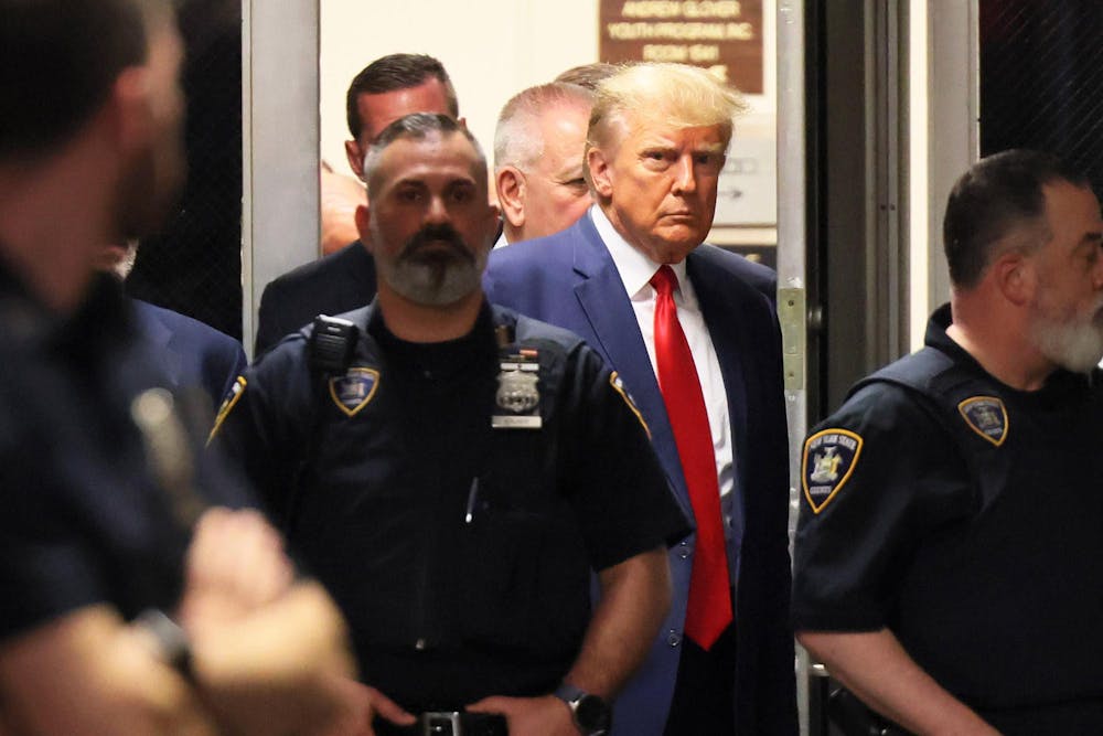 Domald Trump being escorted by policemen through a doorway