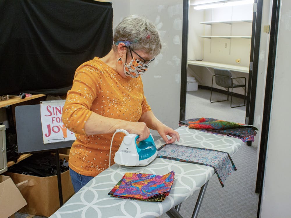 Jean Graham irons fabric before it is sewn Oct. 22, 2021, at the College Mall. She began volunteering with the Bloomington Mask Drive after she retired from being a nurse this year. “We can prevent people from dying,” Graham said. “It’s that simple.”