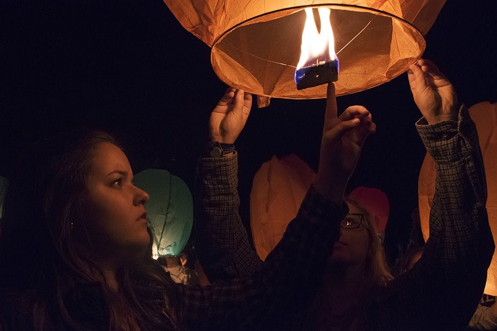 Alpha Delta Pi sorority sisters Betsy Adams and Shayna Melemed light a lantern in honor of Adrian Jimenez Sunday night. 