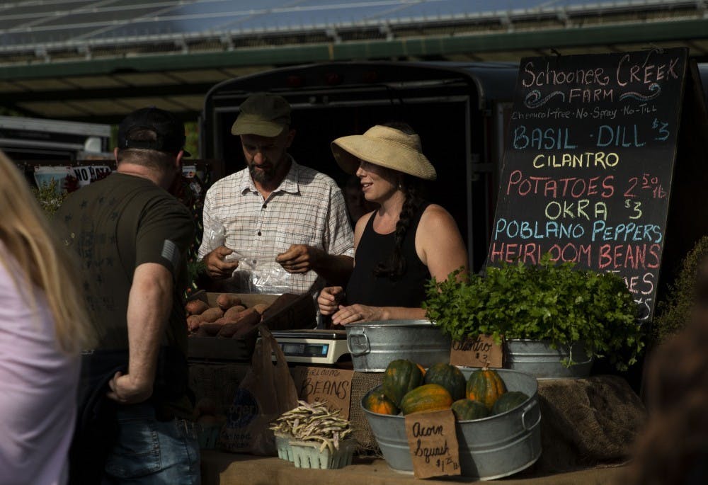 <p>Sarah Dye and her husband Doug Mackey speak to a customer Sept. 28 at their booth for Schooner Creek Farm at the Bloomington Community Farmers’ Market. They filed a lawsuit Friday against the city, mayor and park officials.</p>