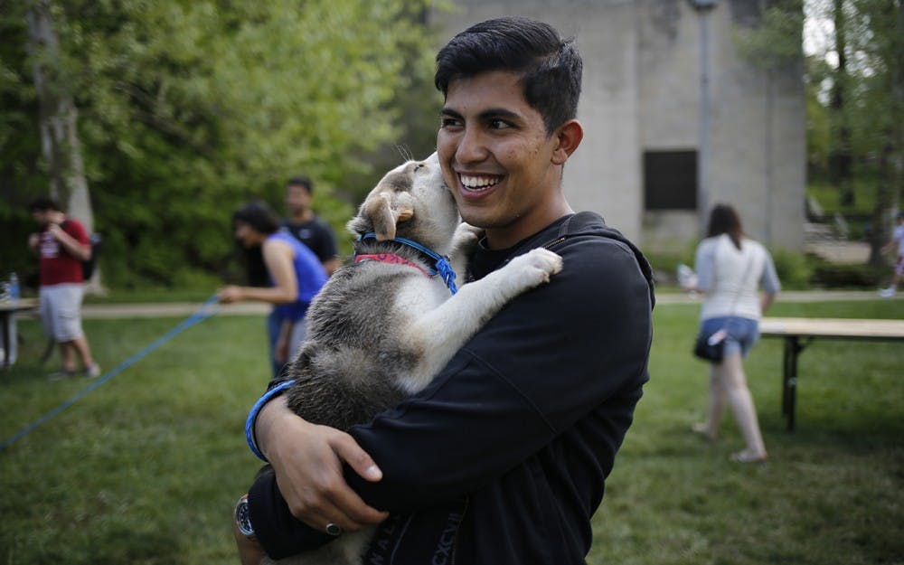 Nikhil Bharadwaj,  volunteer at the City of Bloomington Animal Shelter, holds his recently adopted puppy, Isco, during the Rent-A-Puppy event Thursday, April 28 at Dunn Meadow. The City of Bloomington Animal Shelter will be holding an event throughout the month of October, Adopt-A-Dog, that will reduce the adoption fees for all dogs during October. 