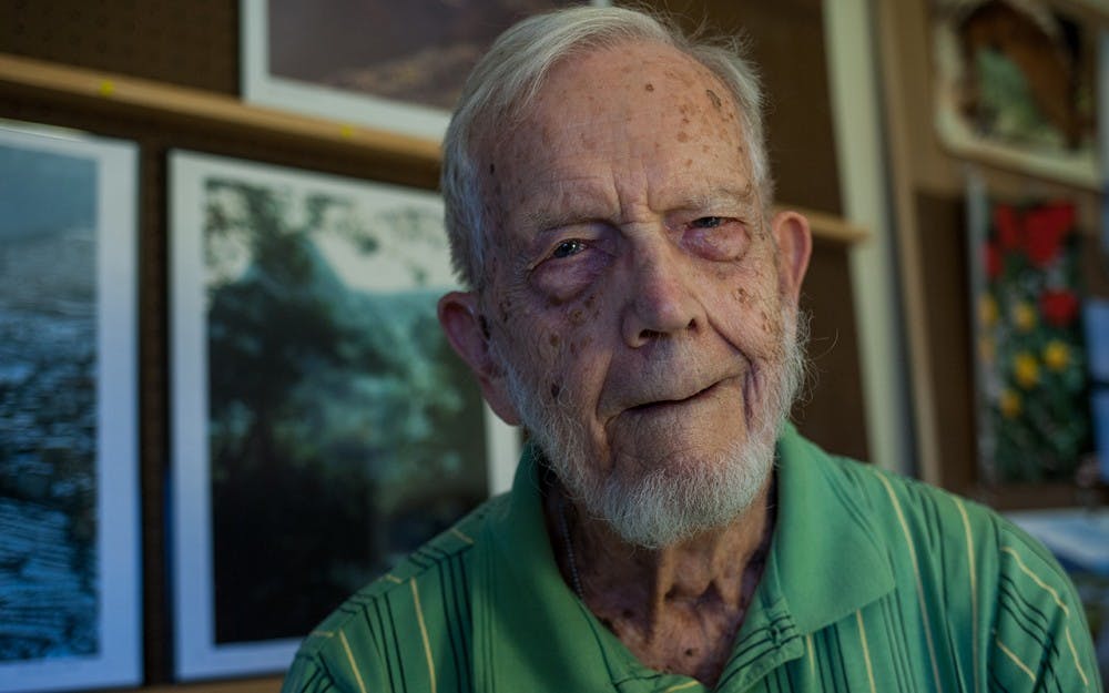 Malcolm "Mac" Fleming, age 97, sits for a portrait in front of his photography gallery at his home in Bloomington on Tuesday evening. Fleming was trained as a still photographer during World War Two, but mostly shot moving pictures. He recently published a book comprised of pictures that he took during his time in Europe during the war entitled "From War to Peace in 1945 Germany: A GI's experience."