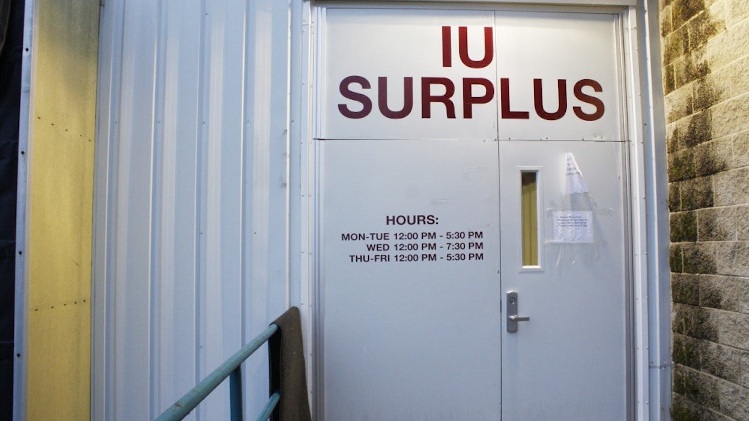 The front doors of Indiana University Surplus Stores display the store's hours. The store is only open Monday through Friday. Monday, Tuesday, Thursday and Friday the store is open 12 - 5:30 p.m., and Wednesday 12 - 7:30 p.m. The warehouse is located at 2931 E 10th Street.
