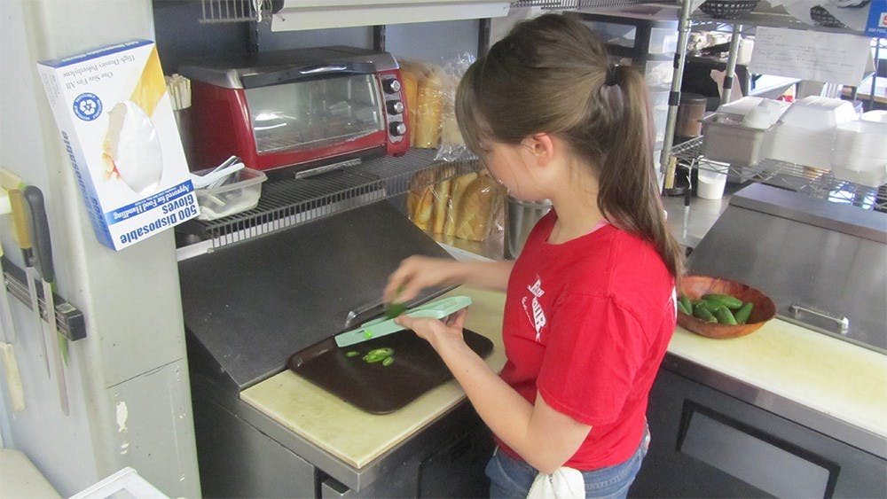 Olivia Stewart, a manager at Rush Hour Station, makes a sandwich in the kitchen of the restaurant Wednesday.  The restaurant owns a food truck that serves food every Friday at the Chocolate Moose.