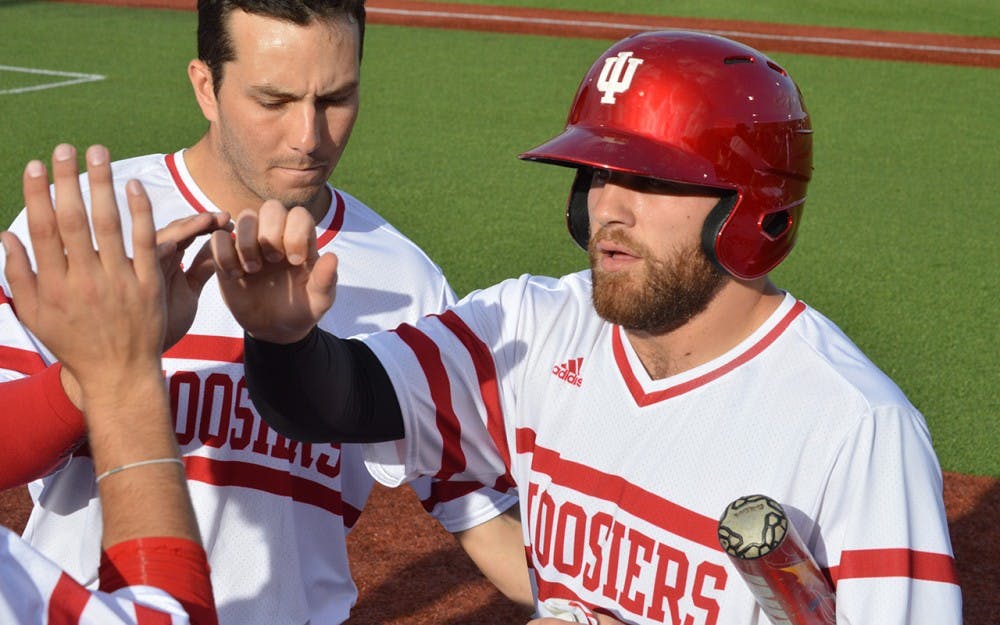 Senior Alex Krupa high-fives his teammates after scoring the first run for the Hoosiers on Tuesday. In IU's game against Ball State, IU&nbsp;finished with a 3-2 win.&nbsp;
