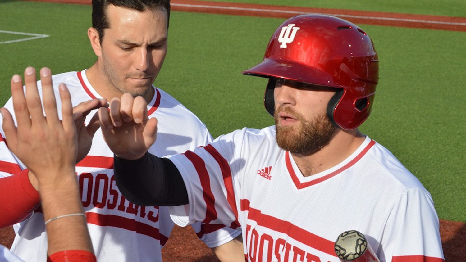 Senior Alex Krupa high-fives his teammates after scoring the first run for the Hoosiers on Tuesday. In IU's game against Ball State, IU&nbsp;finished with a 3-2 win.&nbsp;