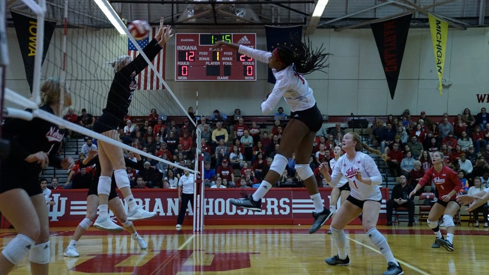 Junior middle blocker Deyshia Lofton spikes the ball against two Nebraska defenders Nov. 17 in University Gym. Lofton finished the season with 281 kills and was named to the All-Big Ten Second Team.&nbsp;