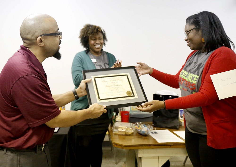 Jay Thomson, left, receives an award from Gloria Howell, member of the Black Graduate Student Association, during the 4th Annual Black Market Friday at the Bethel AME Church.  Thomson runs Hoosier Barber Shop at N. Walnut St. The Black Graduate Student Association hosts the event annually to remember the Black Market which was located on Kirkwood Ave and burned down in 1968 by the Ku Klux Klan. 