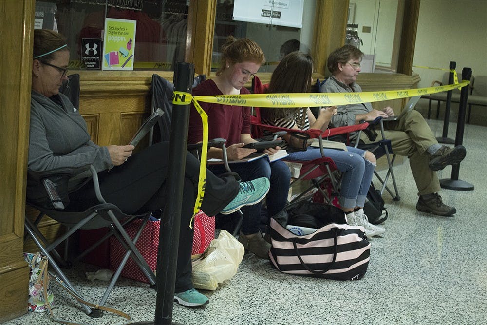 Rebecca and daughter Abigail Miller sit at the front of the line for Tyler Oakley on Thursday night outside of the closed IU Bookstore in the IMU. The Millers got in line around 4 p.m. on Thursday and will be there until at least 8 a.m. Friday until they get a wristband to come back and meet and have a book signed by Oakley at 5 p.m.