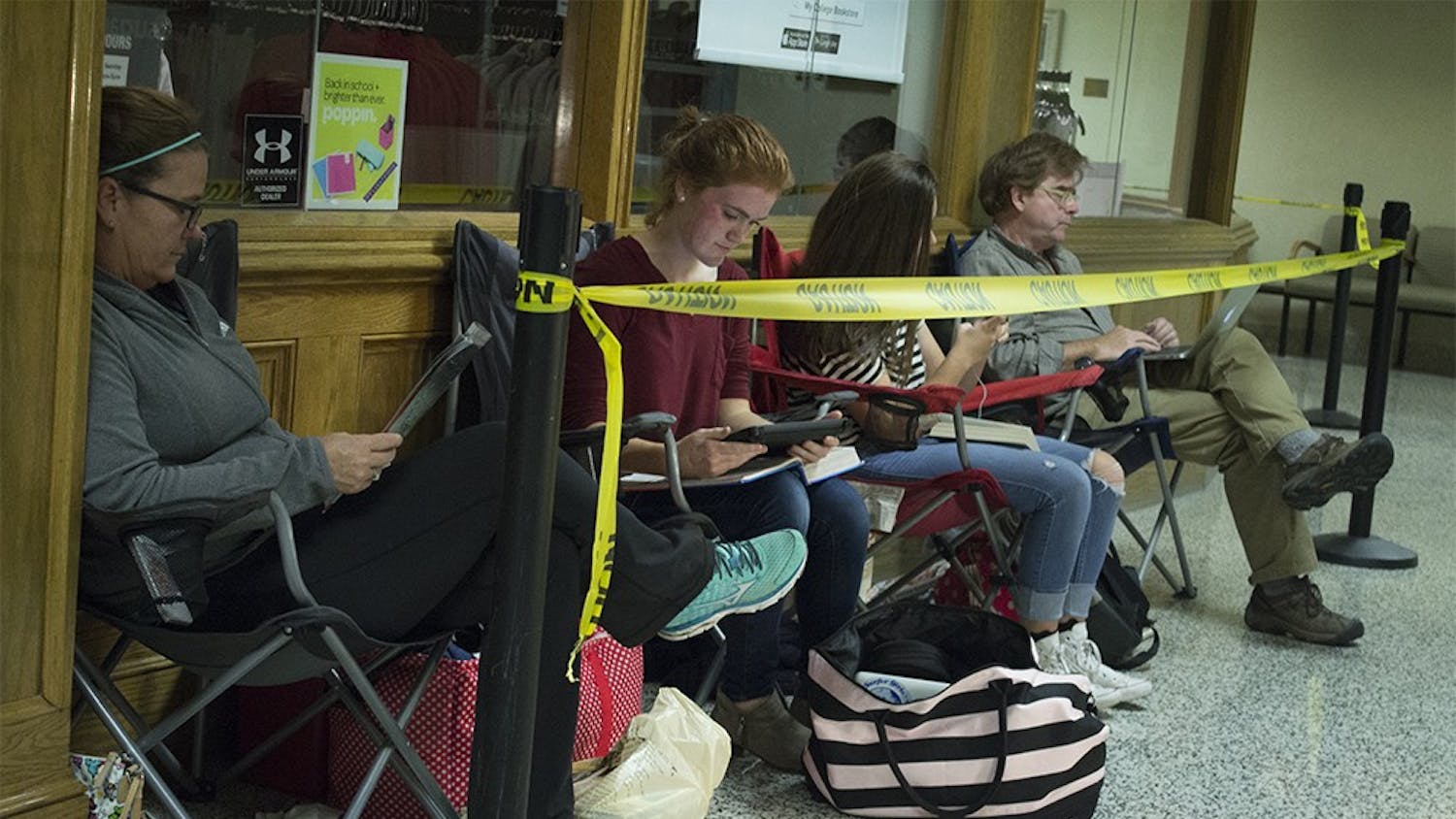 Rebecca and daughter Abigail Miller sit at the front of the line for Tyler Oakley on Thursday night outside of the closed IU Bookstore in the IMU. The Millers got in line around 4 p.m. on Thursday and will be there until at least 8 a.m. Friday until they get a wristband to come back and meet and have a book signed by Oakley at 5 p.m.